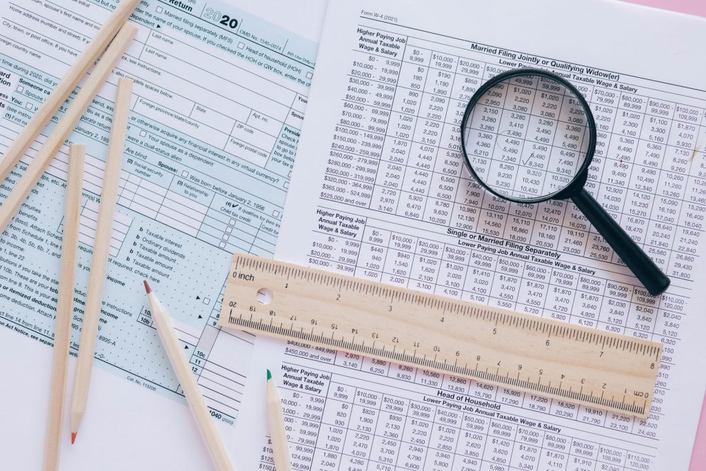 A high angle view showing IRS tax forms with pencils, ruler, and magnifying glass for financial planning.